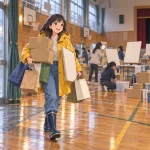 雨の日の体育館へ異なる調達先の物資を運ぶ黄色いレインコート姿の相沢澪